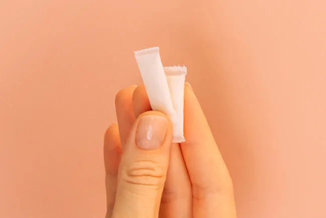 Hand holding two slim white BRYO nicotine-free pouches